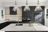 Modern black kitchen with white marble counter tops textured tiles styled to sell